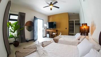 Quarto de hotel com duas camas, ventilador de teto, televisão, planta e abajur.