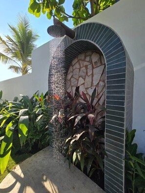 Um espelho de água com parede de pedra e plantas.