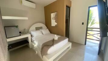 Ein modernes Schlafzimmer mit Bett, Schreibtisch und einer Tür, die auf einen Balkon führt.