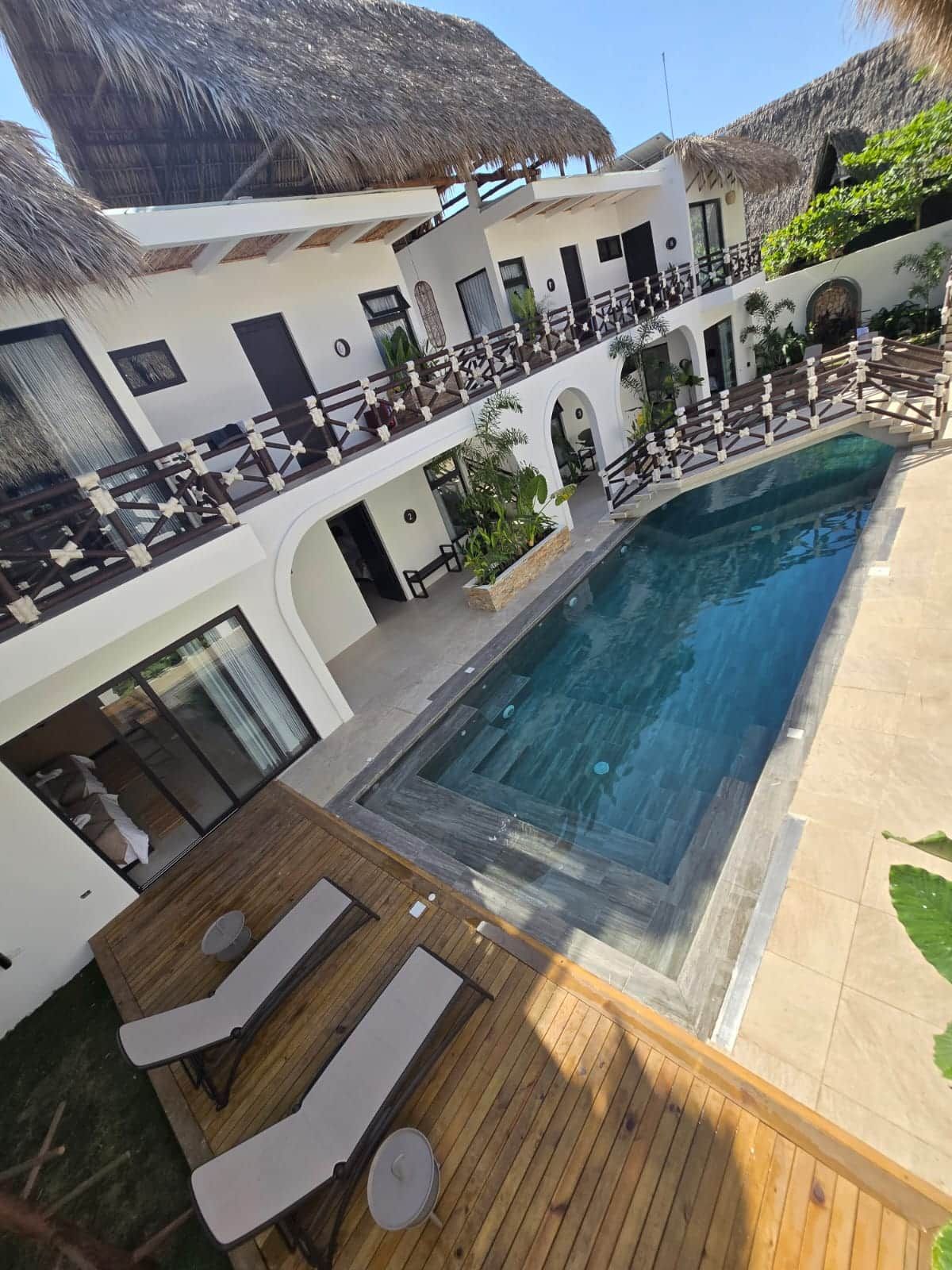 A poolside area with a wooden deck, lounge chairs, and a pool.