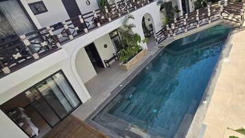 A poolside area with a wooden deck, lounge chairs, and a pool.