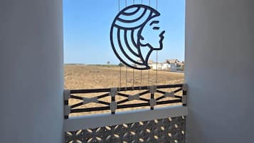 Un balcon doté d’une balustrade aux motifs géométriques, d’un toit de chaume et d’une silhouette représentant le profil d’une femme.