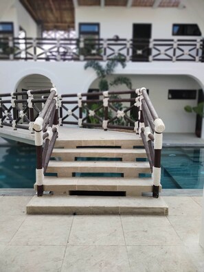 A poolside area with a wooden staircase leading to a balcony.