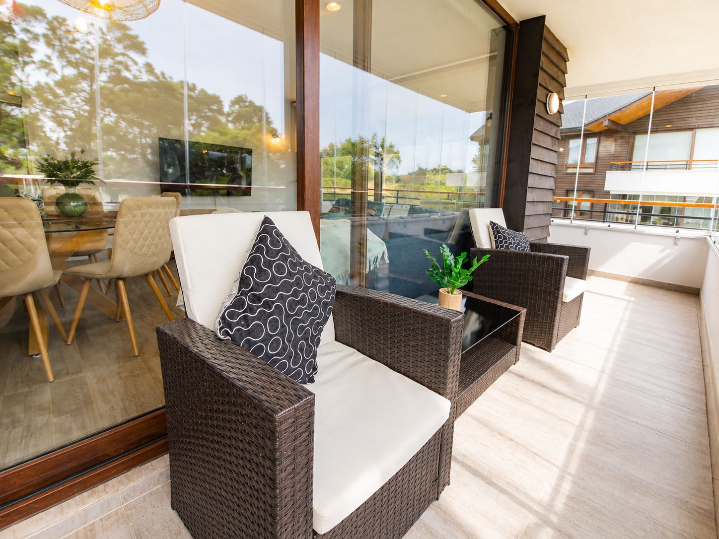 A modern outdoor seating area with wicker furniture and a glass table.