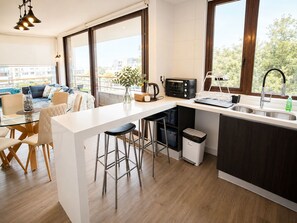Een moderne keuken met een centraal eiland, barkrukken, een magnetron en een spoelbak.