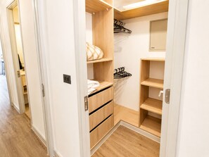 Ein begehbarer Kleiderschrank mit Holzböden, einer Kleiderstange und einem Spiegel.