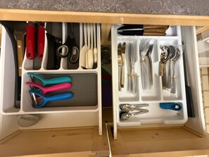 A kitchen drawer with utensils and tools organized in compartments.