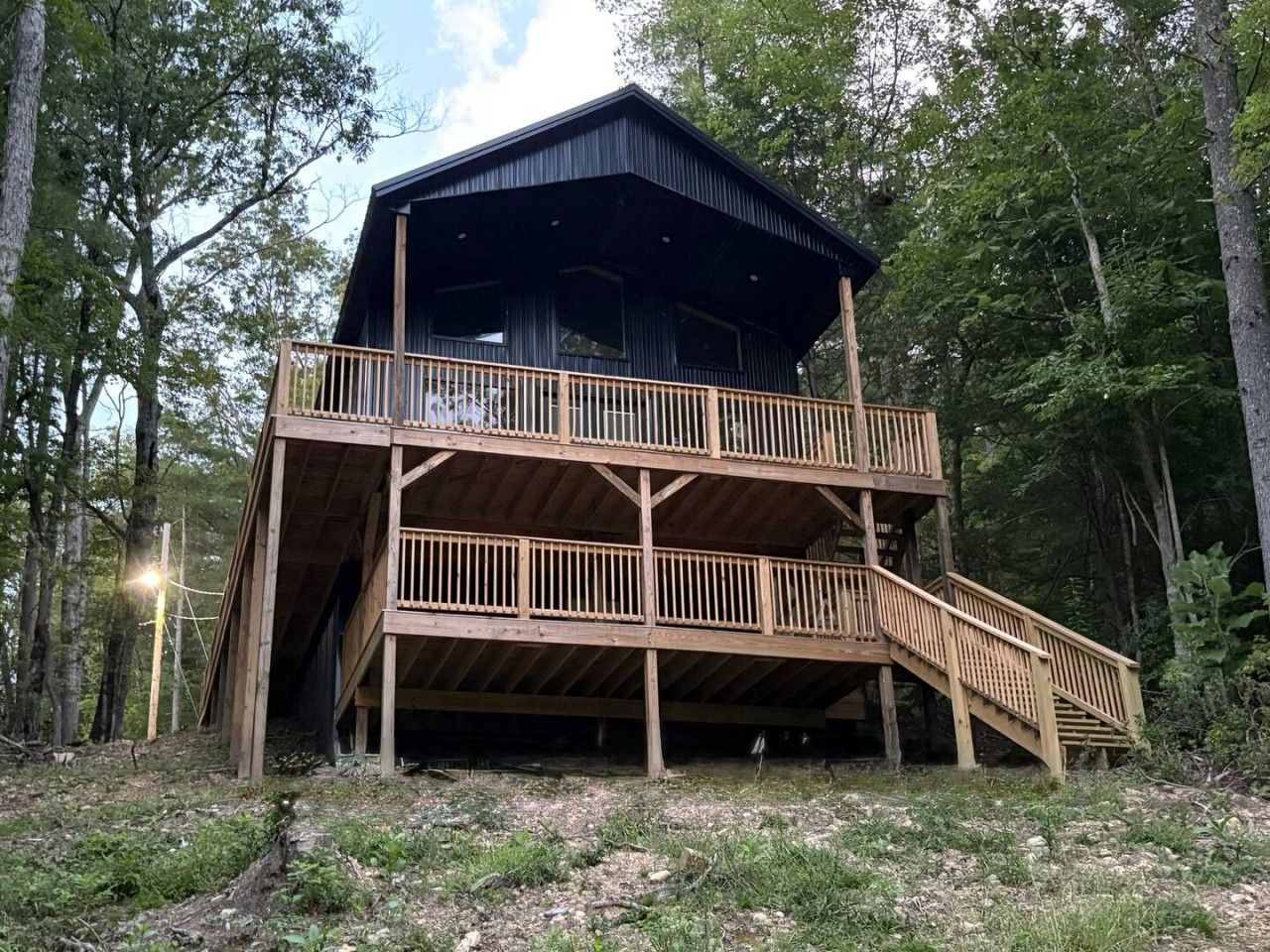 A two-story wooden cabin with a balcony and a staircase.
