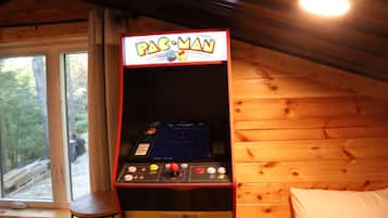A Pac-Man arcade machine in a cabin with wooden walls and a window.