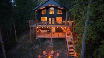 A cabin with a deck, a fire pit, and outdoor seating.