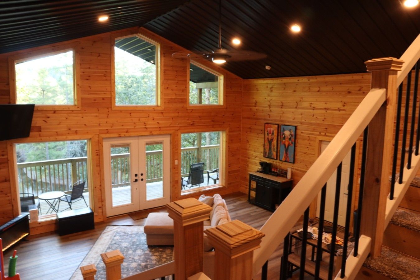A spacious wooden cabin with a large deck, a staircase, and a dining area.