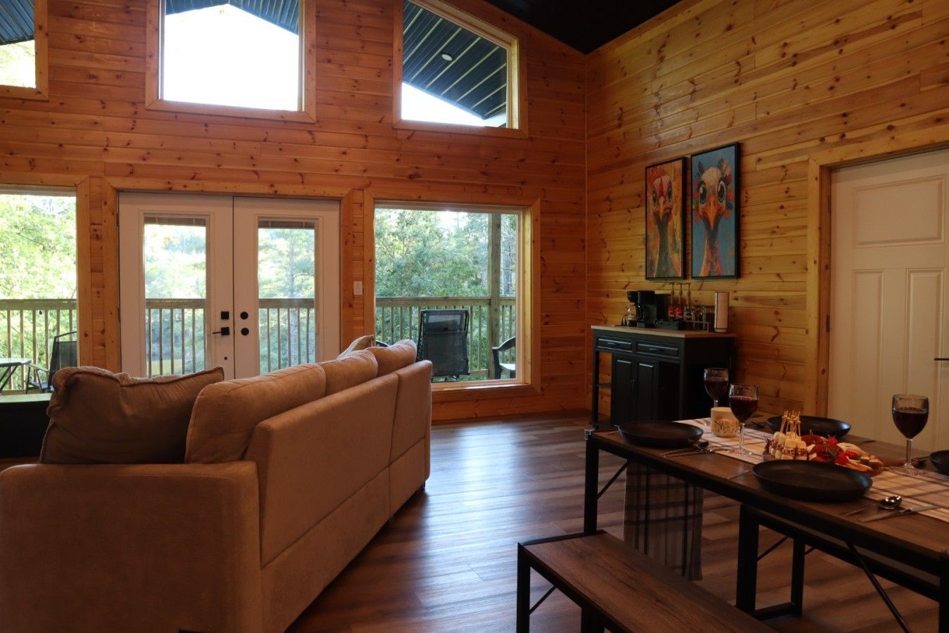 A cozy cabin interior with a sofa, dining table, and artwork on the walls.