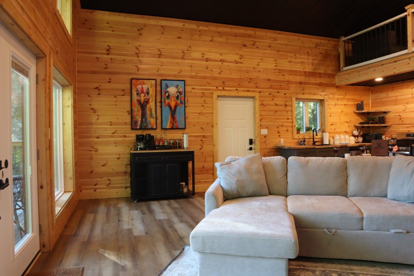 A cozy cabin interior with a wooden interior, a sofa, a coffee station, and artwork on the wall.