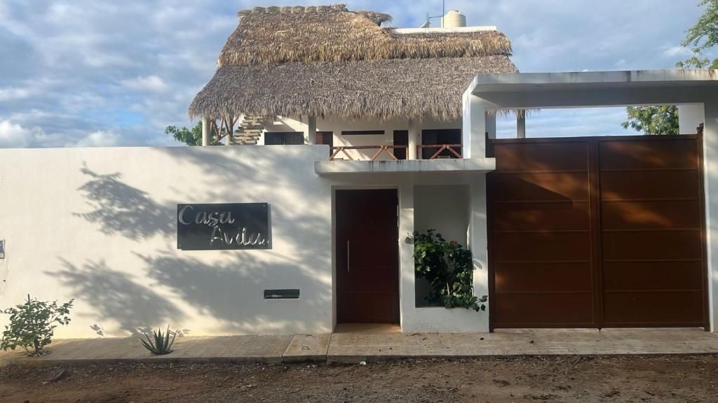 A modern building with a thatched roof, a sign reading 'Casa Linda,' and a gated entrance.