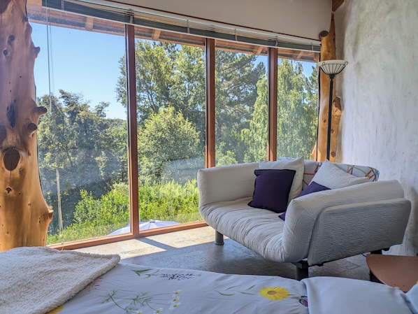 A room with a large window, a sofa, and a bed. - Celestial inn (Pucon)