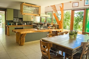 A modern kitchen with a central island, wooden cabinetry, and a large window providing natural light. - Celestial inn (Pucon)
