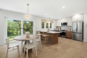 Una cocina moderna con una isla central, electrodomésticos de acero inoxidable y ventanas amplias con vistas al exterior.