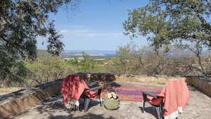 A terrace with a view overlooking a landscape, featuring a table and chairs with a woven basket and a patterned rug. - Maison Camellu – Propriété de charme au cœur des oliviers, vue mer (Calenzana)