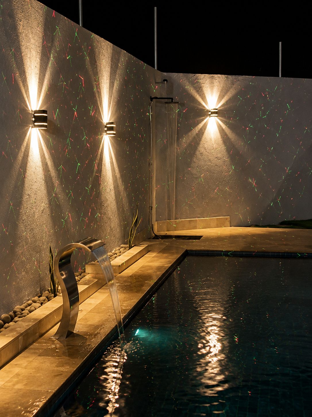 A swimming pool with a water feature and wall-mounted lights.