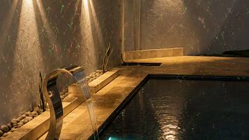 A swimming pool with a water feature and wall-mounted lights.