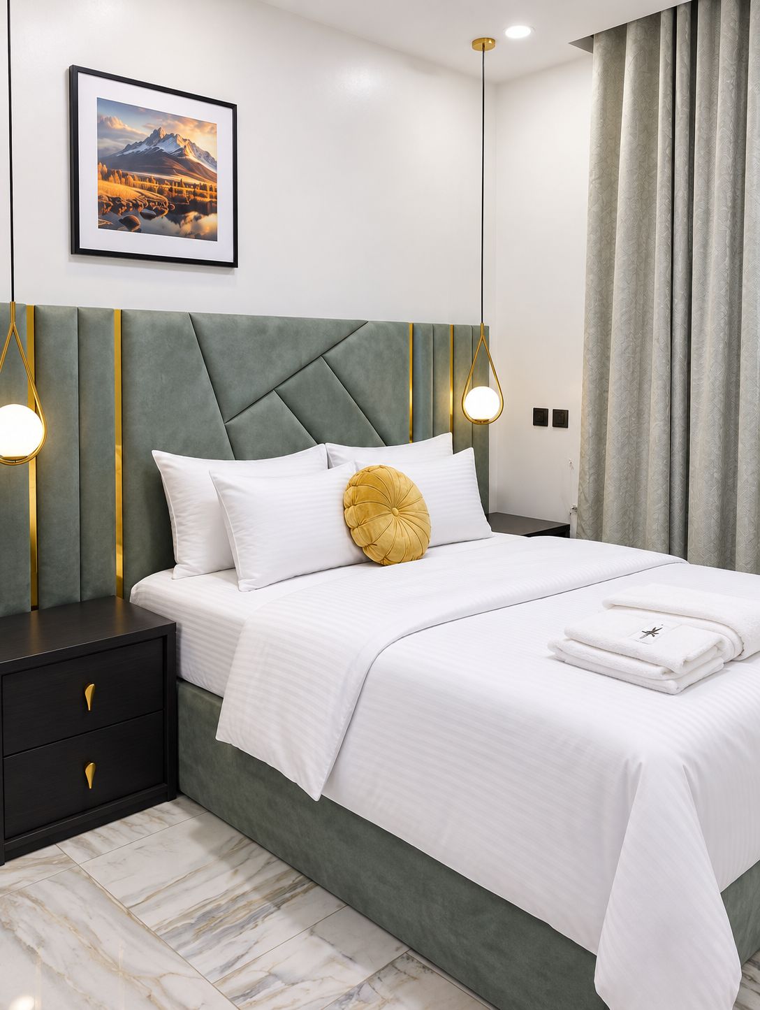 A neatly made bed with white bedding and a single yellow accent pillow, a bedside table with a drawer, and a framed picture on the wall.