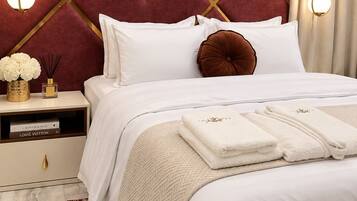 A hotel room with a bed, bedside tables, a nightstand, a decorative wall, and a hanging light fixture.