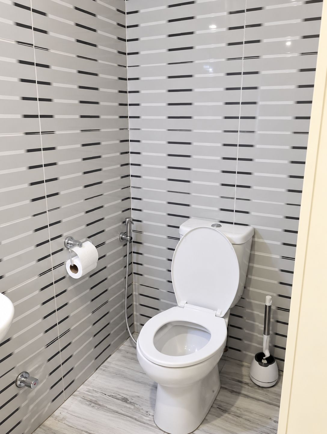 A modern bathroom with a toilet, a toilet paper holder, and a bidet.