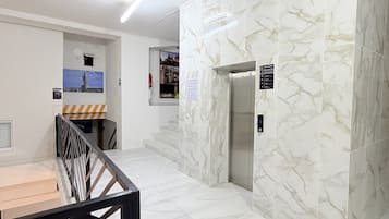 Un interior moderno con paredes de mármol, una escalera y un ascensor.