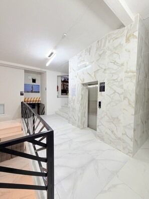 A modern interior with marble walls, a staircase, and an elevator. - Cathedral Centro Histórico D8 (Guadalajara)