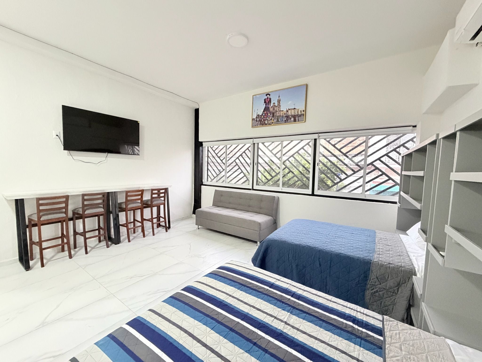 Un dormitorio con cama, sofá, televisión y un comedor con sillas.