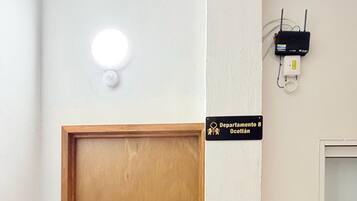 A wooden door with a handle, a light fixture above it, and a sign indicating 'Departamento 8 Ocotlán' on the wall.