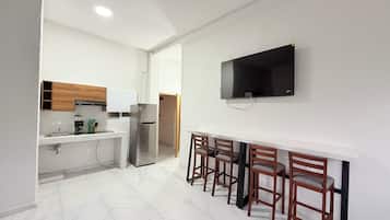 A compact kitchen with a built-in oven, a refrigerator, and a wooden cabinet.