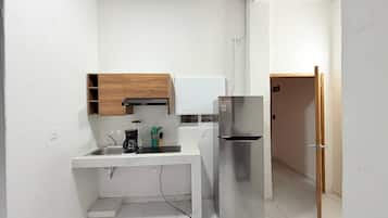 A compact kitchen with a built-in microwave, a stainless steel refrigerator, and wooden cabinets.