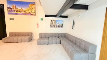 A modern waiting area with a sectional sofa, a fire extinguisher, and two framed pictures on the wall.