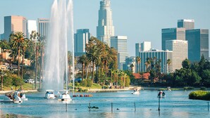 Eine Skyline mit modernen Gebäuden, einem großen Brunnen und Booten auf einem See.