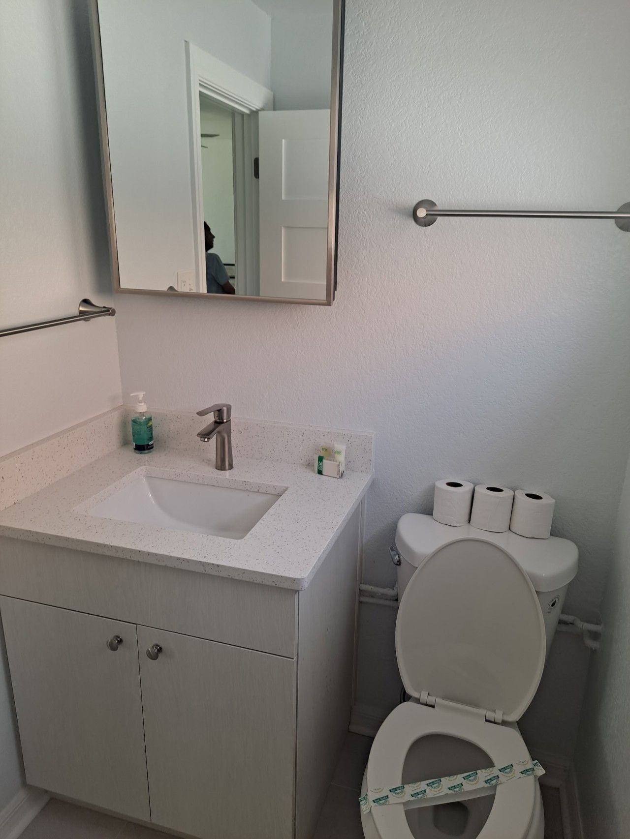 A bathroom with a white sink, mirror, toilet, and a towel rack.