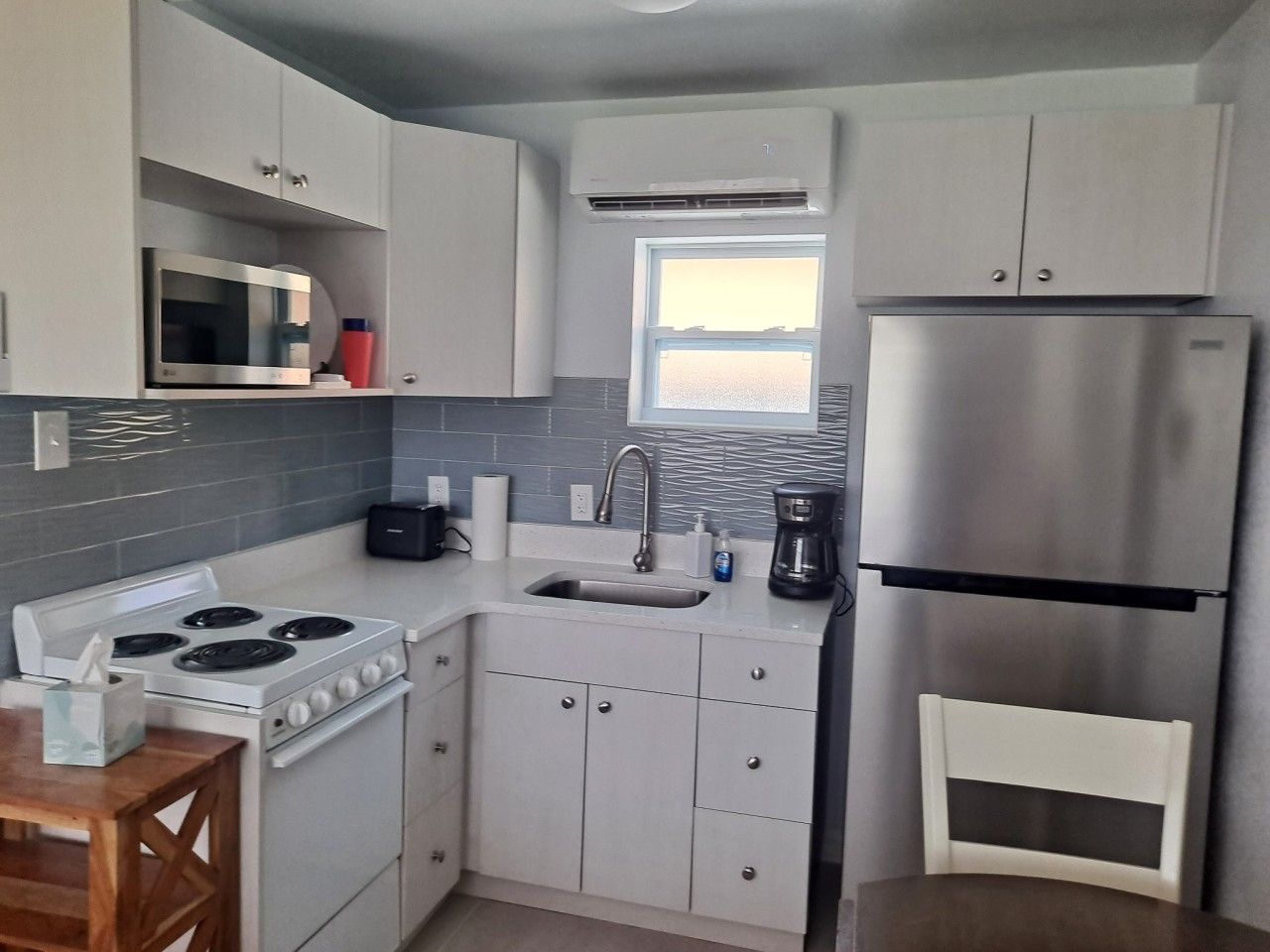 A compact kitchen with a stove, microwave, sink, and refrigerator.