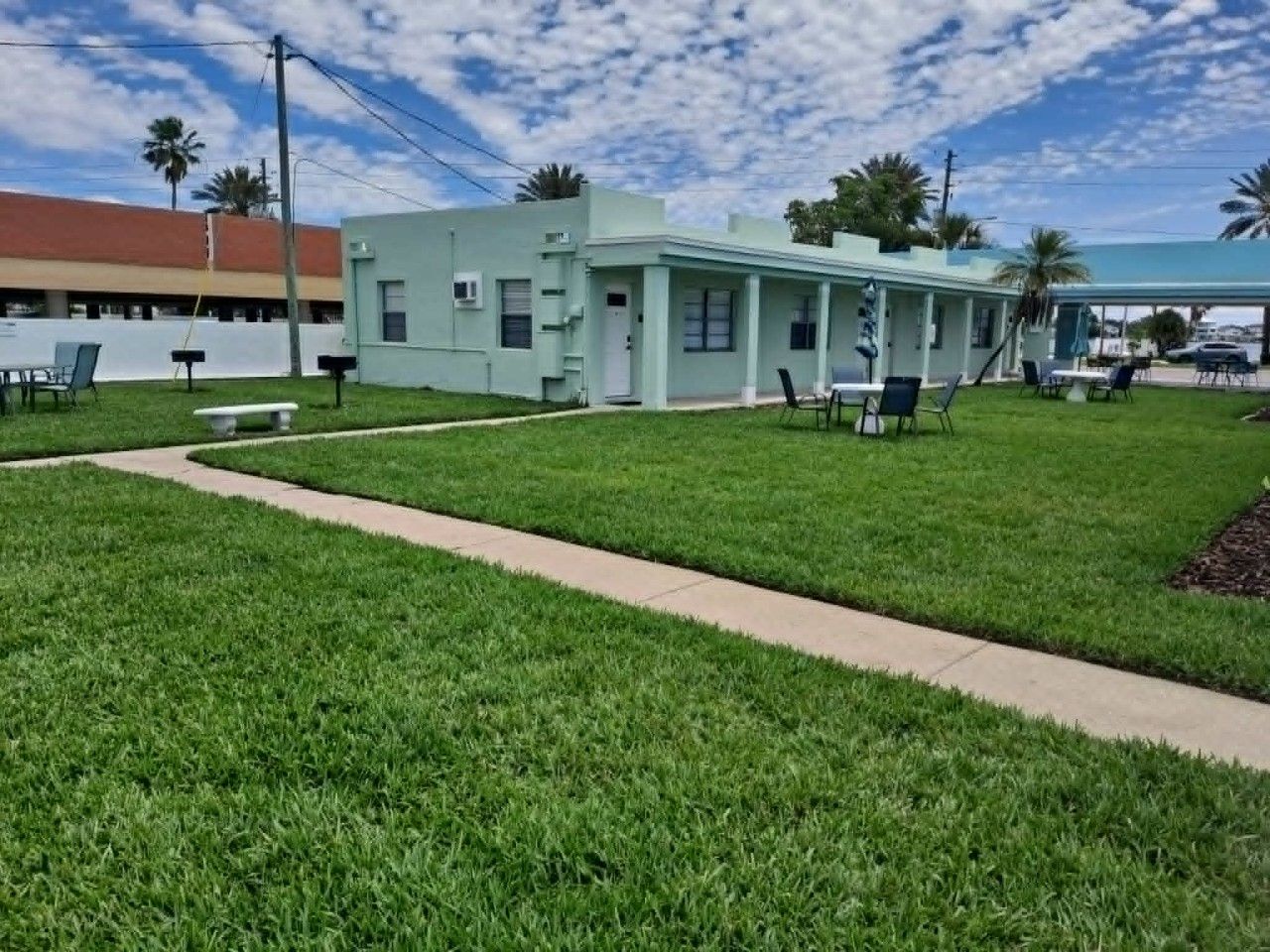 A building with a flat roof, a covered outdoor seating area, and a paved walkway.