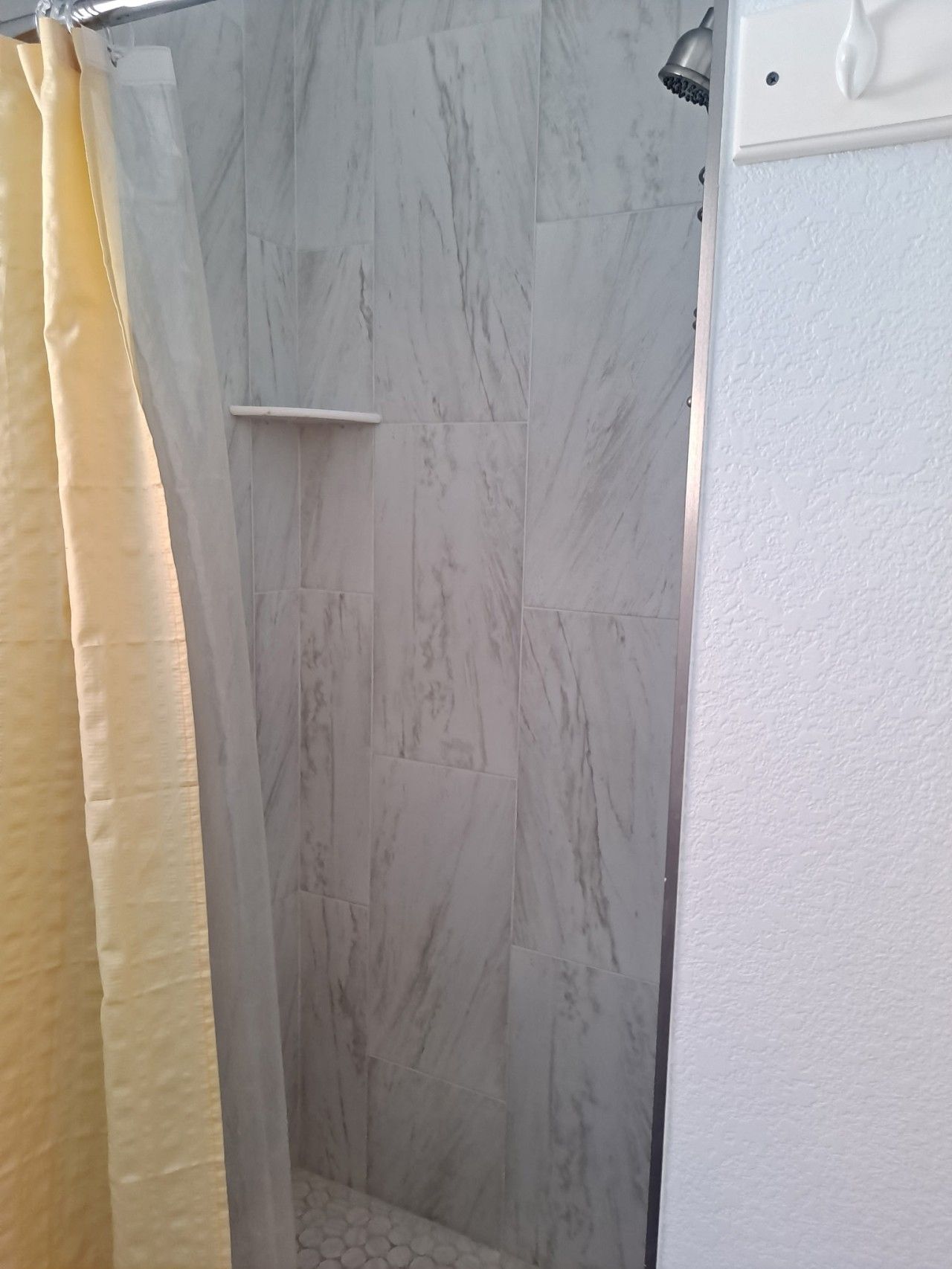 Un espace douche avec un mur en marbre et une porte blanche.