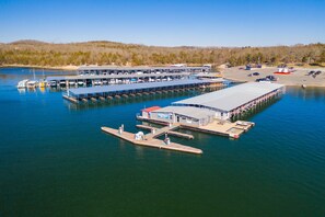 A marina with multiple docks and boats, a large building with a flat roof, and a parking area. - Gold Rush-less then a half mile to Silver Dollar City! (Branson)