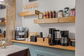 A kitchen with wooden shelves holding various items, a coffee maker, and a framed picture. - Gold Rush-less then a half mile to Silver Dollar City! (Branson)