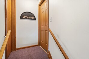 A hallway with a wooden door, a welcome sign, and a carpeted floor. - Colerain King Suite - 30+ Day Stay (Groesbeck)