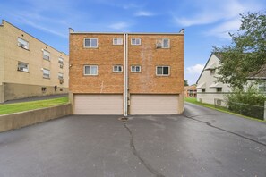 A two-story building with a garage entrance, brick facade, and multiple windows. - Colerain King Suite - 30+ Day Stay (Groesbeck)