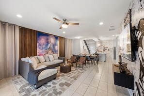 A modern living room with a sofa, coffee table, and dining area. - 7BR Disney Escape  Pool, Spa, Theater & Arcade (Kissimmee)