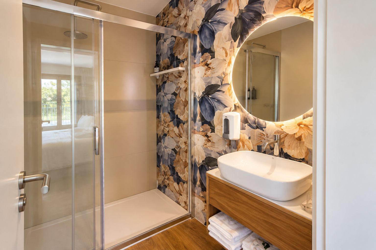 A modern bathroom with a glass shower enclosure, a wooden vanity with a sink, and a floral wallpaper design.