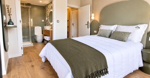 A bedroom with a bed, bedside tables, a nightstand, a bathroom with a shower, a toilet, and a sink. - House Park (Gandra)