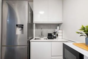 A modern kitchen with a stainless steel refrigerator, a water dispenser, a sink, and a coffee maker. - Central London 2-Bedroom Apartment on Leather Lane | Sleeps 6 | (London)