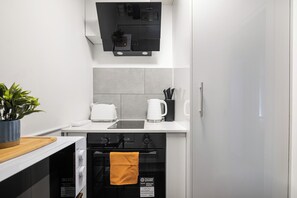 A compact kitchen with a built-in oven, a coffee maker, and a toaster. - Central London 2-Bedroom Apartment on Leather Lane | Sleeps 6 | (London)