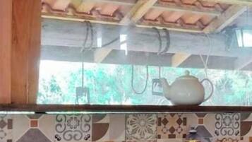 Una cocina con salpicadero de azulejos, un colgador de ollas y diversos utensilios de cocina sobre la encimera.