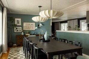 A dining area with a long table, chairs, a vase, and wall art. - Denver Dream Retreat w/Hot Tub, Sauna, Movie & Game Rms, Putting Green, Fire Pit (Arvada)